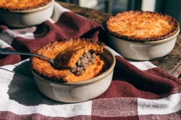 escondidinho de batata doce gratinado em travessas individuais, com porções cruas embaladas para congelar