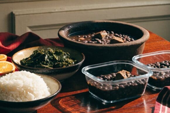 panela de feijoada light com cortes magros ao lado de couve refogada, arroz e potes porcionados para congelar