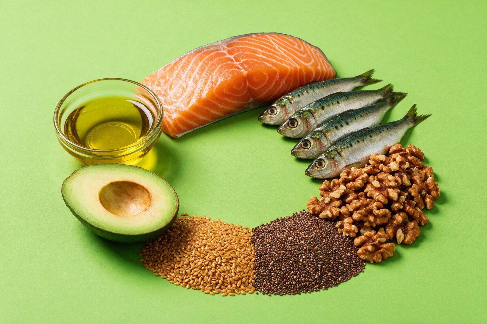 Alimentos ricos em ômega 3 — salmão, sardinha, nozes, chia, linhaça, abacate e azeite — dispostos em círculo sobre fundo verde-limão