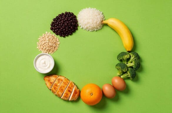 Alimentos do dia a dia — feijão, arroz, banana, brócolis, ovos, laranja, frango e aveia — dispostos em círculo sobre fundo verde-limão