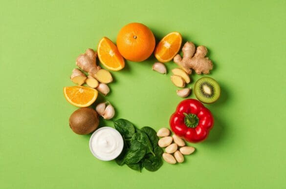 Alimentos que ajudam a imunidade — laranja, gengibre, alho, kiwi, pimentão, espinafre, iogurte e castanha-do-pará — sobre fundo verde-limão