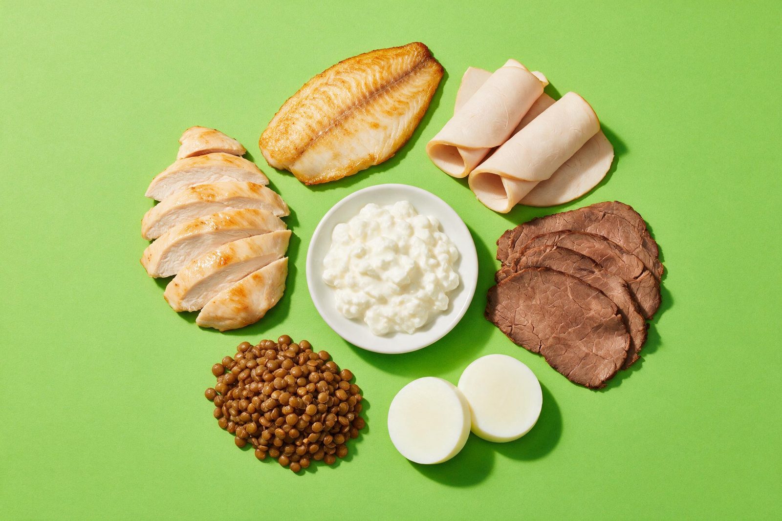 Proteínas magras — frango grelhado, tilápia, peito de peru, carne bovina magra, cottage, claras e lentilha — sobre fundo verde-limão