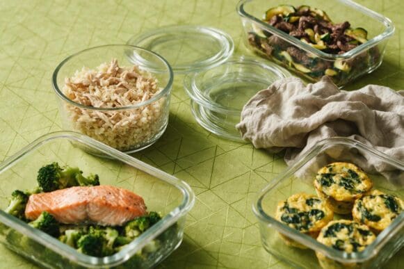 Quatro potes de vidro com receitas low carb prontas para congelar sobre toalha verde-limão da Frutifica